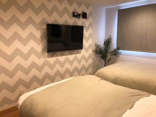 a bedroom with two beds and a flat screen tv at Time - Vacation STAY 18884v in Kagoshima