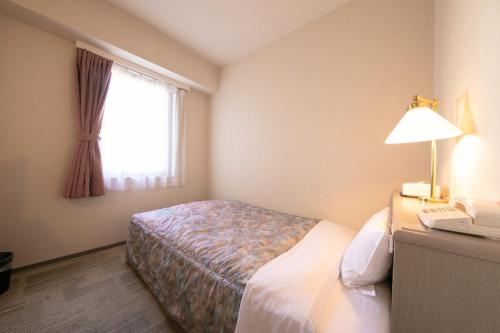 a hotel room with a bed and a desk with a phone at Main Hotel - Vacation STAY 82545 in Miyakonojō