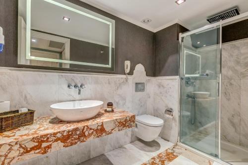 a bathroom with a sink and a shower and a toilet at Antmare Hotel in Alaçatı