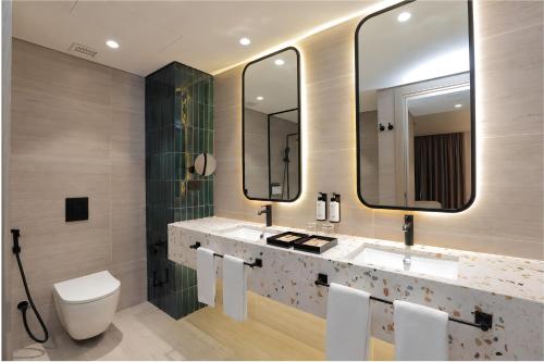 a bathroom with two sinks and a toilet and mirrors at voco Beirut Central District by IHG in Beirut