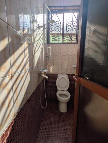 a small bathroom with a toilet and a window at New Africa one inn in Dar es Salaam