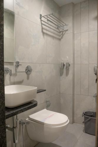 a white bathroom with a toilet and a sink at Hotel Emirest in Bhilad