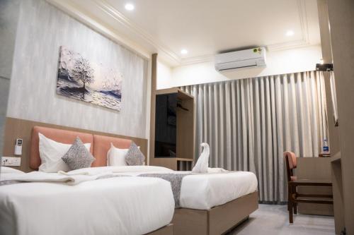 a hotel room with two beds and a desk at Hotel Emirest in Bhilad