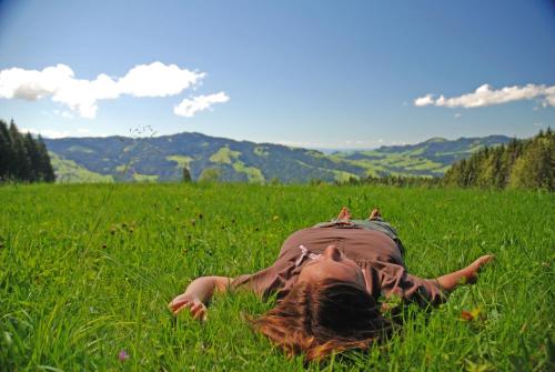 a person laying in the grass in a field at Sonnmatt Bergpension & Gesundheitszentrum in Ebnat