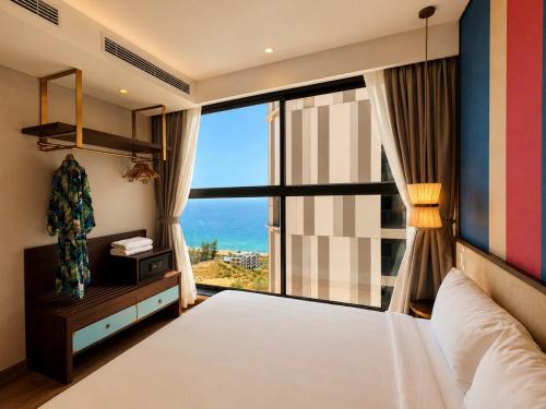 a bedroom with a bed and a large window at Mandala Cham Bay Mũi Né in Mui Ne