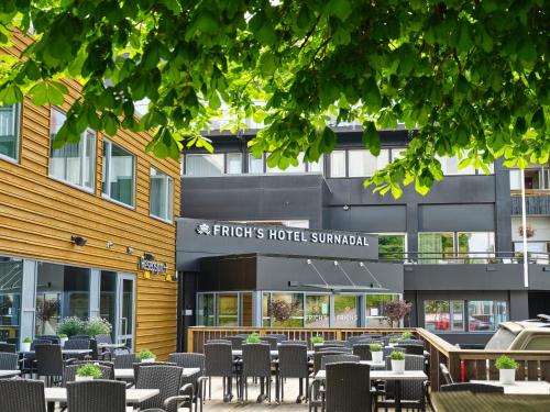 a restaurant with tables and chairs in front of a building at Frich`s Hotel Surnadal in Surnadal