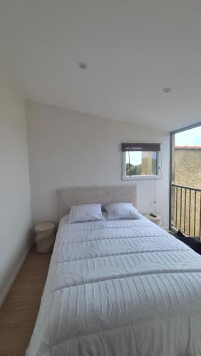 a large white bed in a bedroom with a window at Between Calvi and Ile Rousse seaside in Lumio