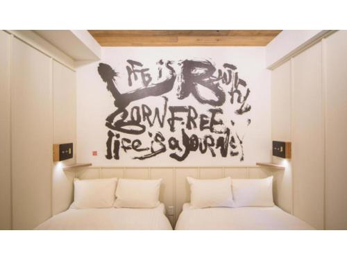 two beds in a room with writing on the wall at Kamon Hotel Namba - Vacation STAY 37029v in Osaka