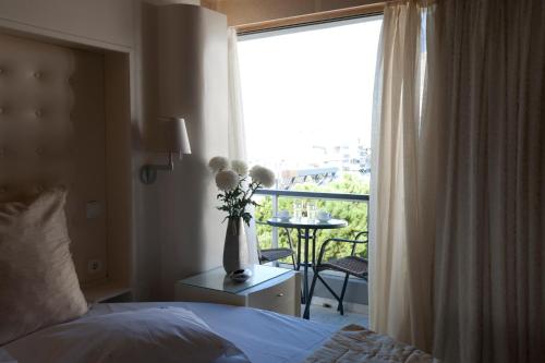 a bedroom with a bed and a window with a vase of flowers at The Crystal Blue Hotel in Athens