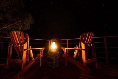 two chairs with a candle sitting on a deck at night at Leopard Mountain Safari Lodge in Manyoni Private Game Reserve