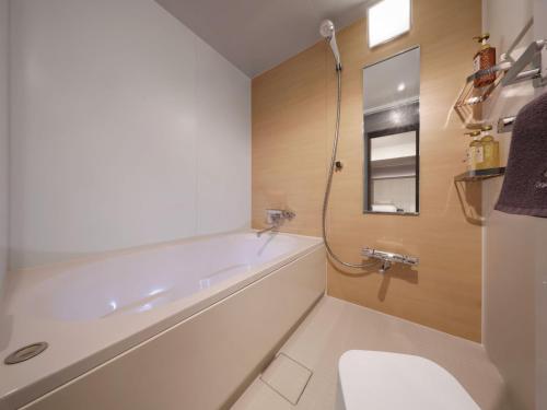 a bathroom with a tub and a toilet and a sink at Dotonbori Crystal Hotel - Vacation STAY 77468v in Osaka