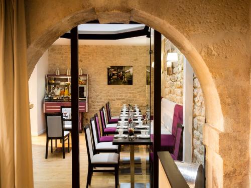 une salle à manger avec une longue table avec des chaises violettes dans l'établissement Hôtel Jacques de Molay - Fitness & Sauna, à Paris
