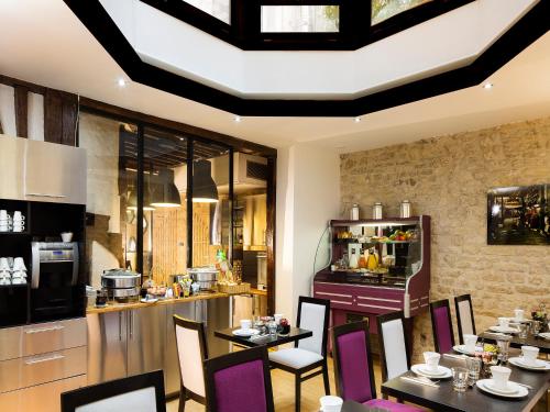 パリにあるHôtel Jacques de Molay - Fitness & Saunaのテーブルと椅子とキッチンのあるレストラン