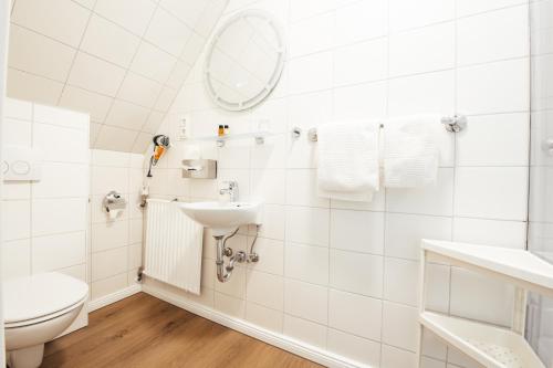 a white bathroom with a toilet and a sink at Hotel Gut Funkenhof in Sundern