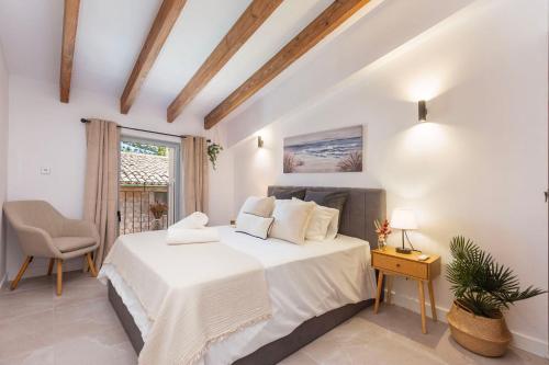 a white bedroom with a bed and a chair at Can Perla in Sóller