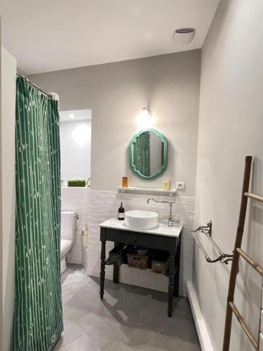 a bathroom with a sink and a green shower curtain at Maison malouna in Saint-Thibéry