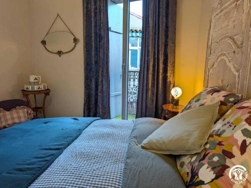 a bedroom with a bed with blue sheets and a window at Maison malouna in Saint-Thibéry