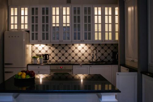 a kitchen with white cabinets and a bowl of fruit on a counter at Royal Residence by OTR in Krakow