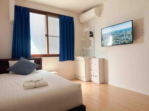 a bedroom with a bed with blue curtains and a television at D Hotel - Vacation STAY 14103v in Tokyo