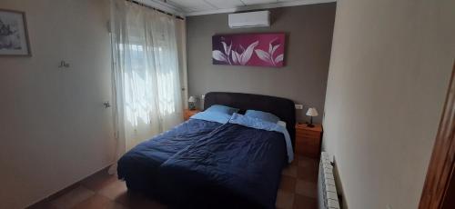 a bedroom with a bed with blue sheets and a window at Mas Solana in Huércal-Overa