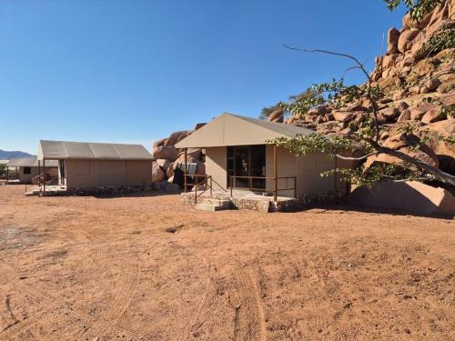 a building in the middle of a desert with a mountain at Sky and Stone Tented Camps in Twyfelfontein