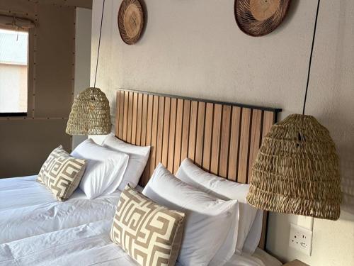 a bedroom with a bed with white pillows and two lamps at Sky and Stone Tented Camps in Twyfelfontein