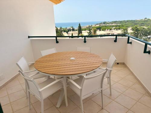 a wooden table and chairs on a balcony with a view at Balaia Plaza in Albufeira