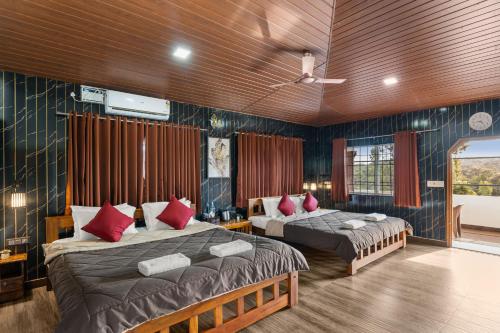 a bedroom with two beds with red pillows at Hatti Eden Coorg in Gonikoppal