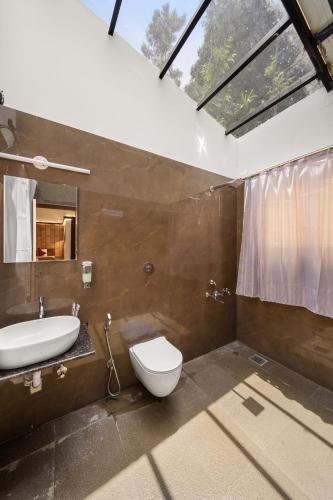 a bathroom with a toilet and a sink and a shower at Hatti Eden Coorg in Gonikoppal