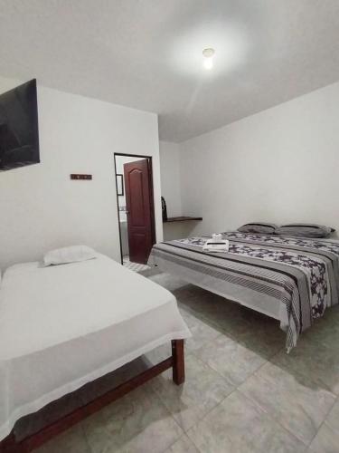 a bedroom with two beds and a tv on the wall at Hospedaje Dora in Máncora
