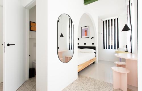 a white bedroom with a bed and a mirror at Duesette Rooms in Filottrano