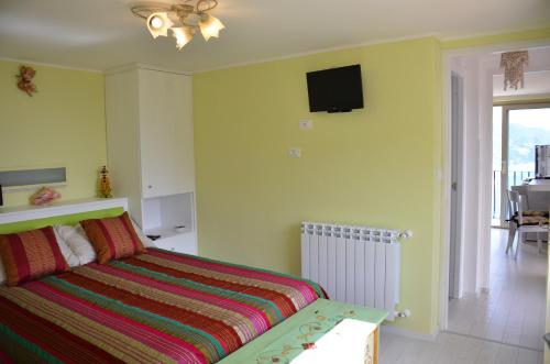 sypialnia z łóżkiem i telewizorem na ścianie w obiekcie Apartment L'Attico w Taominie