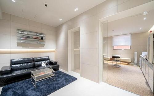 ein Wohnzimmer mit einer schwarzen Ledercouch und einem Tisch in der Unterkunft aiden in Busan