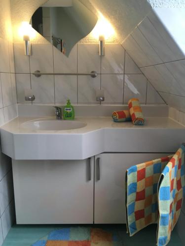 a white bathroom with a sink and a mirror at Ferienhaus Kirchturmblick bei Quedlinburg in Hoym