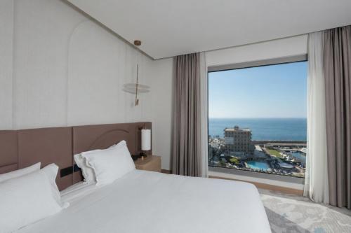 a bedroom with a large bed and a large window at voco Beirut Central District by IHG in Beirut