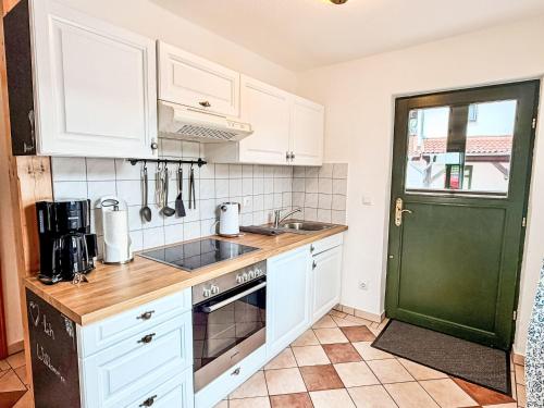 a kitchen with white cabinets and a green door at Apartment Bornholm by Interhome in Dargun
