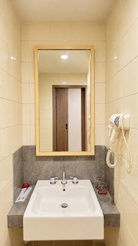 a bathroom with a white sink and a mirror at Alltrue Lite Hotel Nagoya Hill Batam in Nagoya