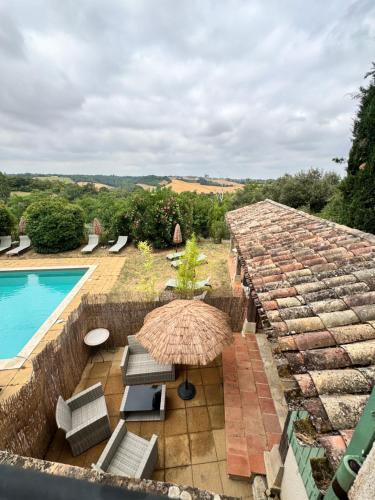 an outdoor patio with an umbrella and a swimming pool at Cuq en Terrasses in Cuq-Toulza