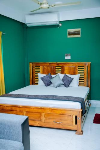 a bedroom with a wooden bed with green walls at JAI REST In in Jaffna