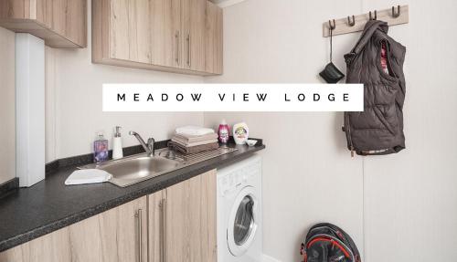 a kitchen with a sink and a washing machine at Meadow View Lodge in Tattershall
