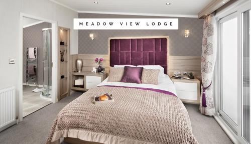 a bedroom with a large bed with a purple headboard at Meadow View Lodge in Tattershall