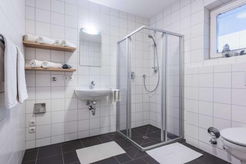 a white tiled bathroom with a shower and a sink at Ferienwohnung Unterlechner - Apt 3 in Vomp