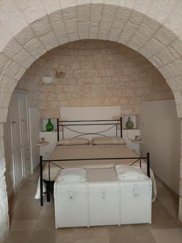 a bedroom with a bed in a stone wall at Trullo Le Tre Sorelle in Cisternino