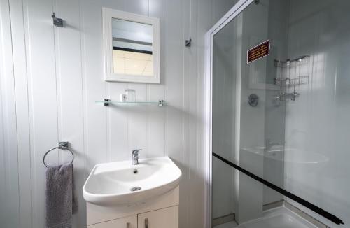 a white bathroom with a sink and a shower at SleepOver Phabeni in Hazyview