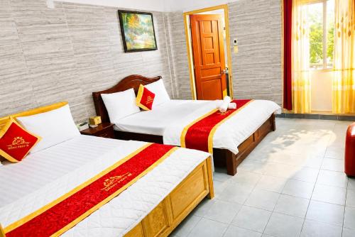 two beds in a hotel room with a door at Hồng Phát 68 Hotel in Ho Chi Minh City