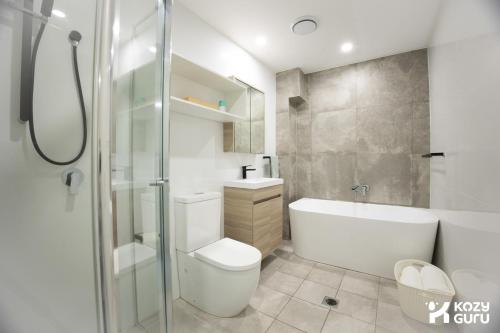 a bathroom with a toilet and a sink and a shower at KozyGuru | Epping | Stylish 1 Bedroom Apartment in Epping
