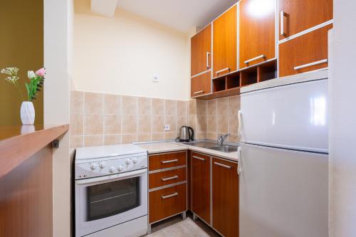 a kitchen with white appliances and wooden cabinets at Apartments Bečić in Budva