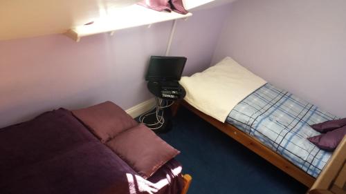 a small bedroom with a bed and a tv in it at Molyneux Guesthouse in Weymouth