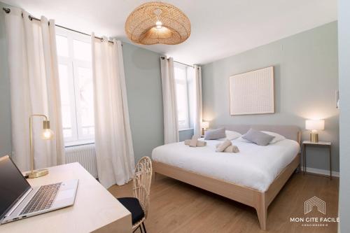 a bedroom with a bed and a desk with a laptop at Gîte LE VAUBAN - Mon Gîte Facile in Colmar