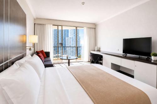 a hotel room with a large bed with a flat screen tv at Level 20 King Bed Suite with Ocean Views in Gold Coast